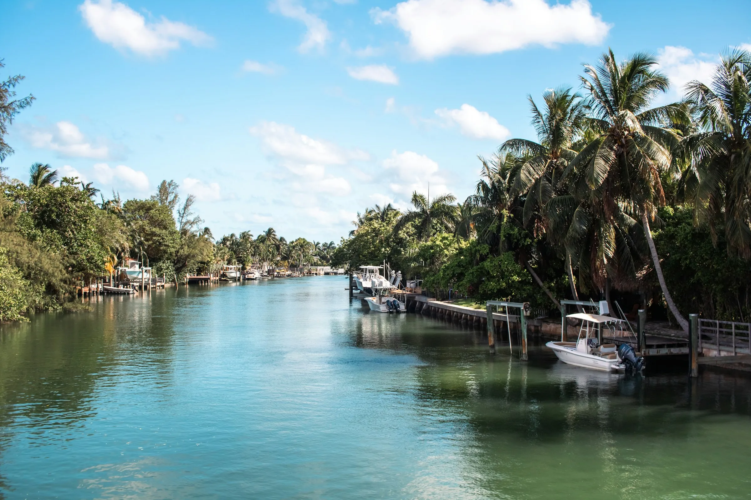 Palm-lined canal in Miami Beach with private docks and small boats