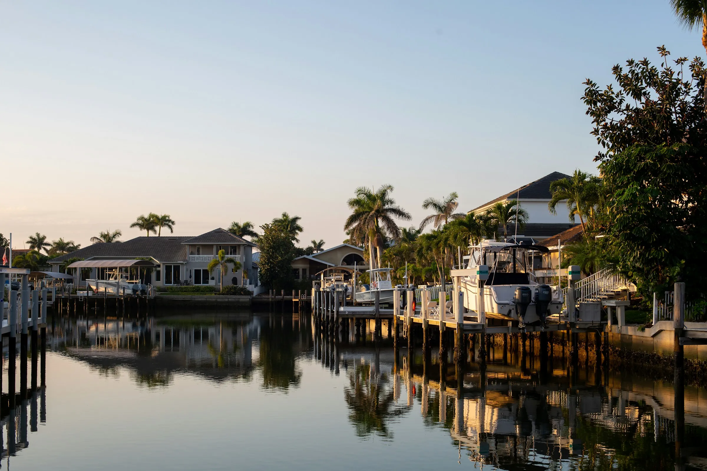 Wooden docks and pilings in front of canal-front homes at dusk