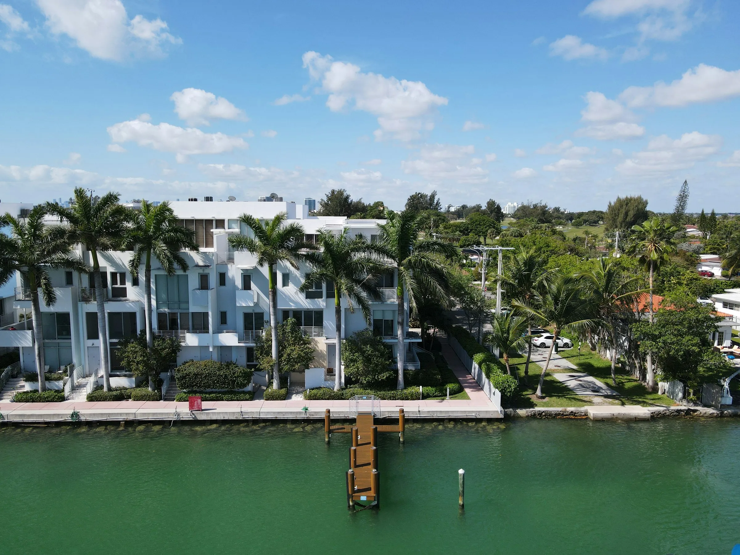 New concrete seawall and small dock in front of waterfront townhomes on a Miami Beach canal