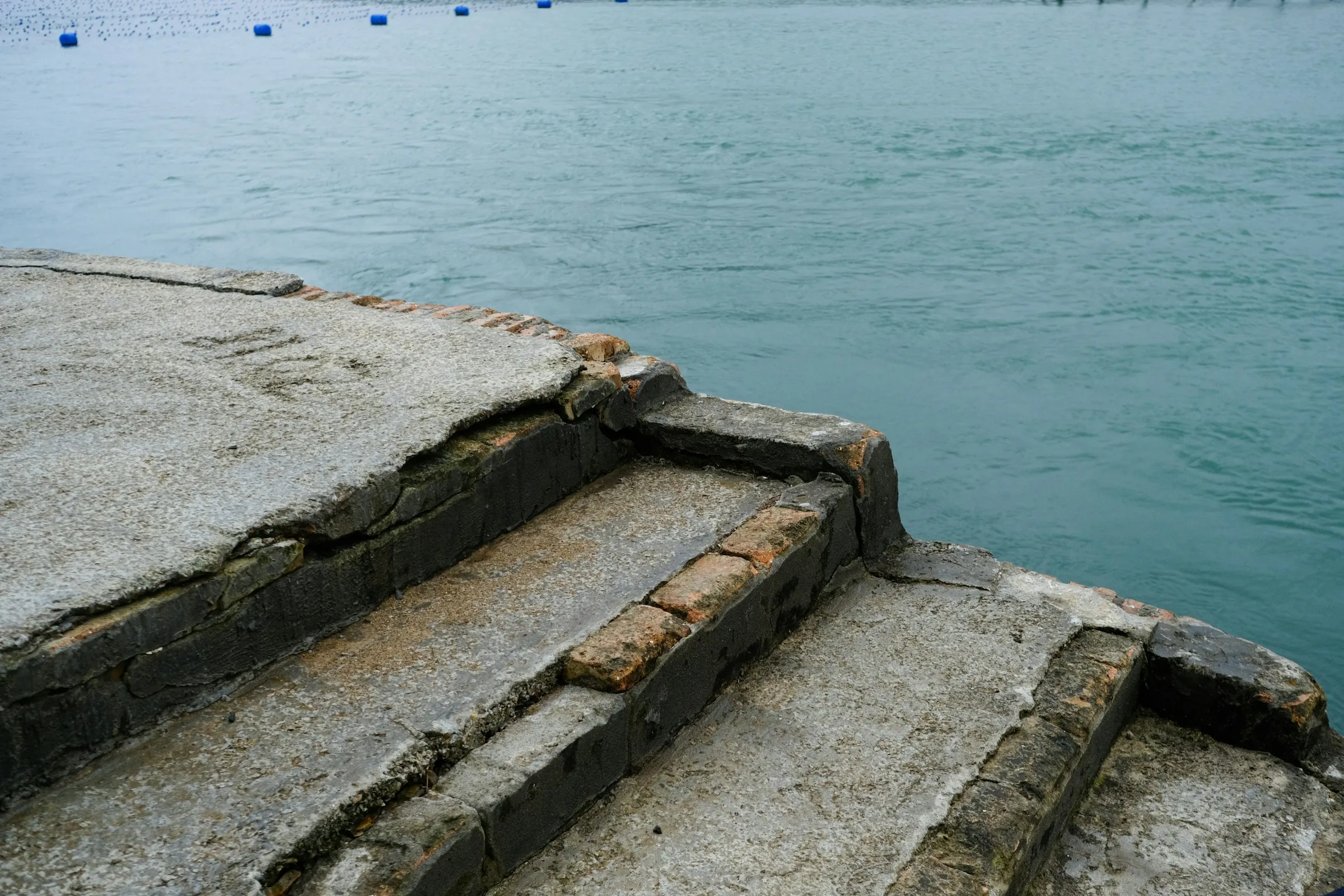 Cracked and settling concrete seawall cap at the water's edge
