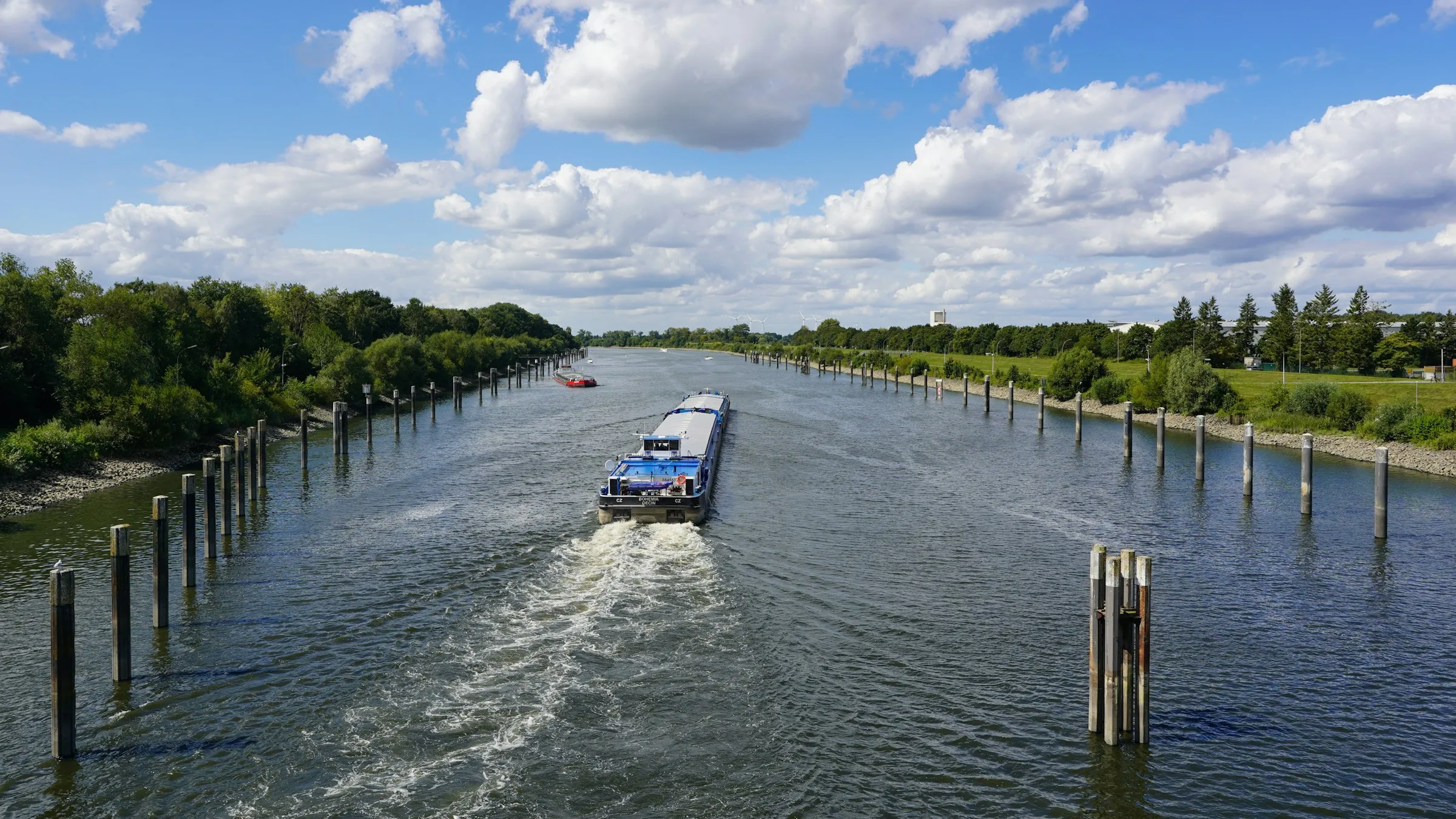 Boat wake washing against wooden pilings along a canal